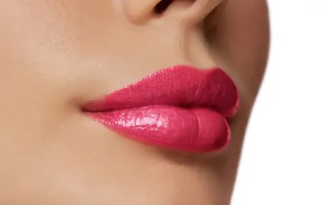 Primo piano labbra femminili con rossetto rosa.
