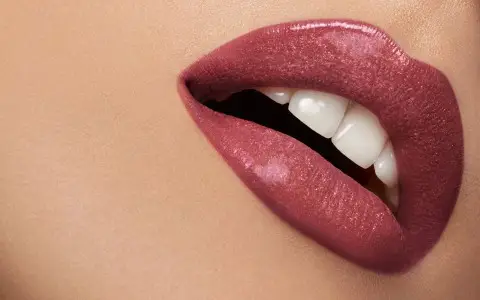 Primo piano labbra scintillanti con rossetto rosa.